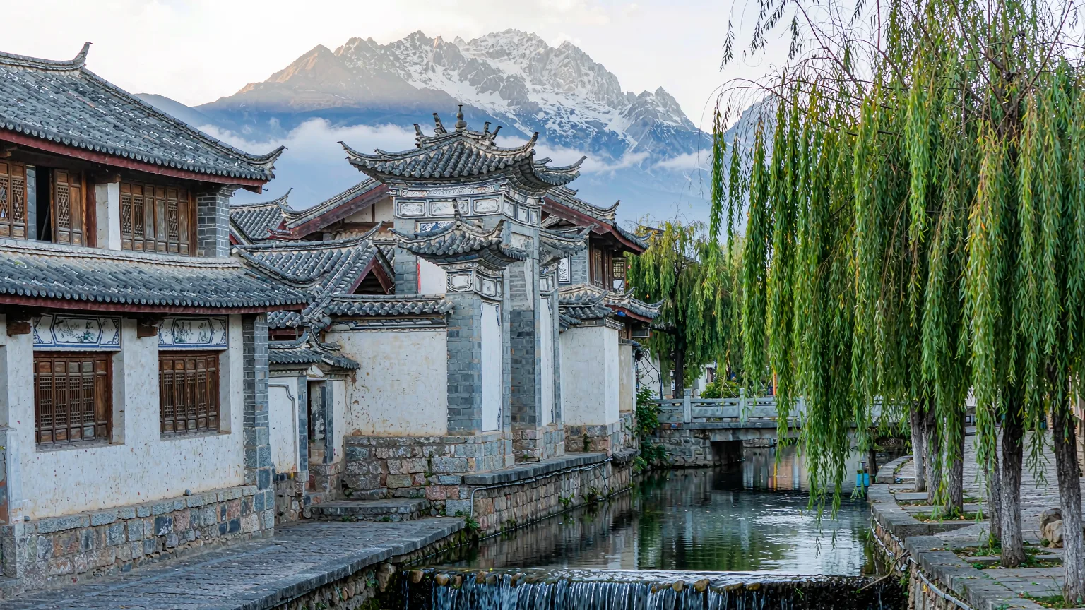 Traditional Naxi mud-brick houses and willow-lined stream in Baisha