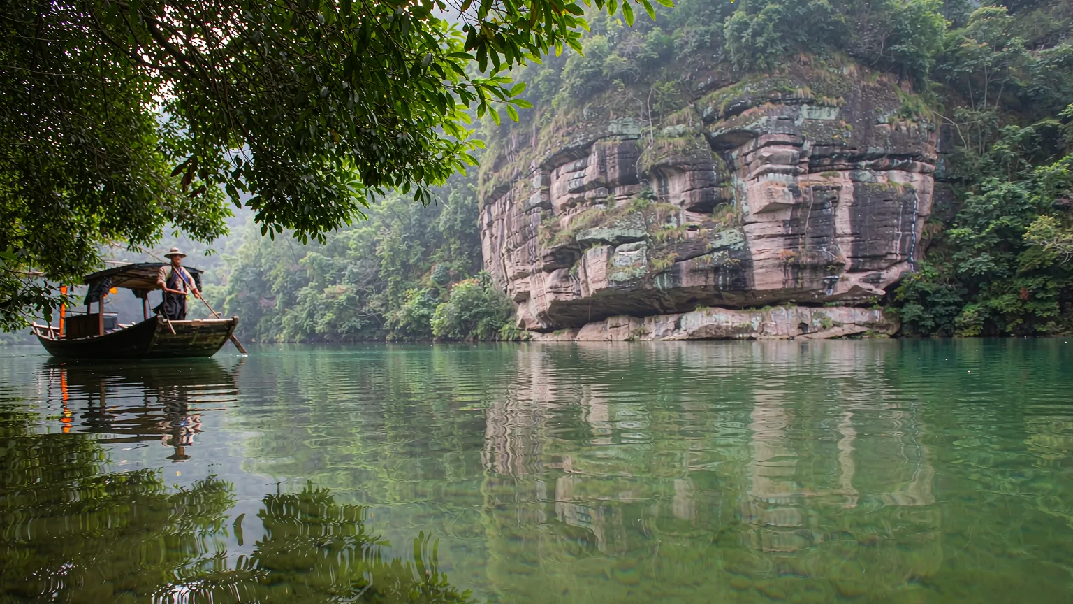 Close-up of Baofeng Lake water reflecting a peak with a Tujia guide in a boat