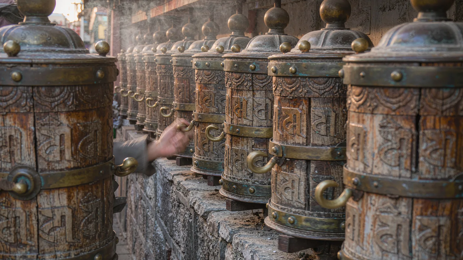 Close-up of prayer wheels along Barkhor Street with pilgrim's hand spinning