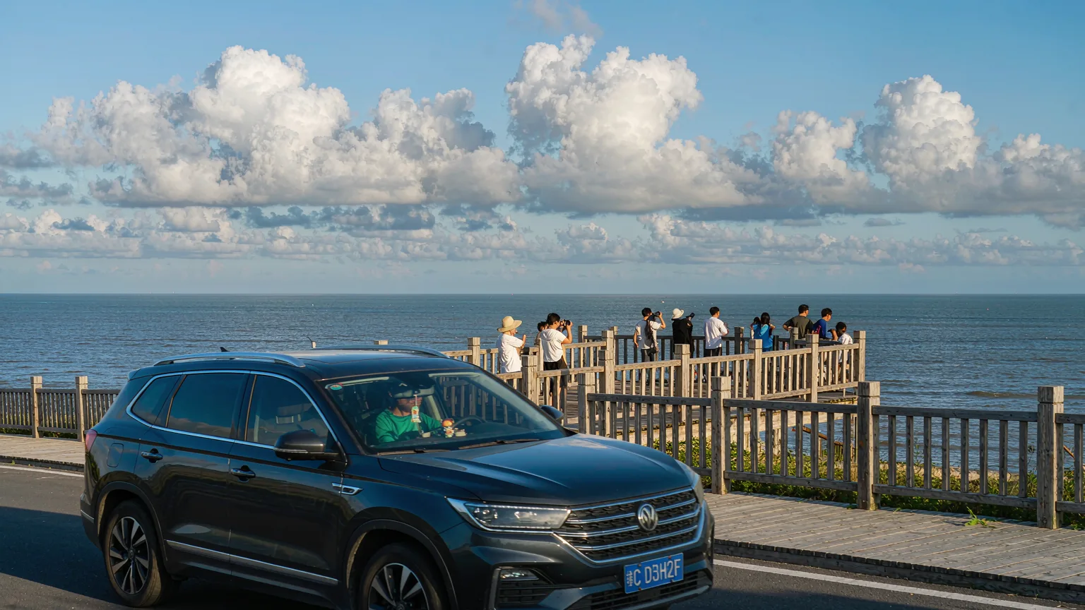 Private car on Binhai Road arriving at a coastal overlook with boardwalk