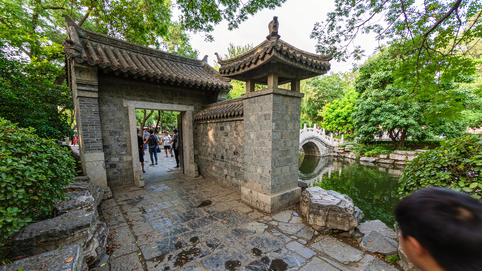 Tourists walking on stone path toward Black Dragon Pool Park entrance