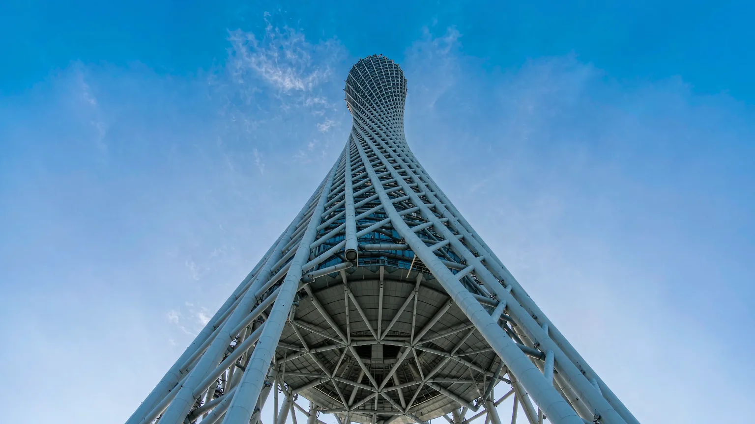 Twisted steel lattice of Canton Tower against blue sky from below