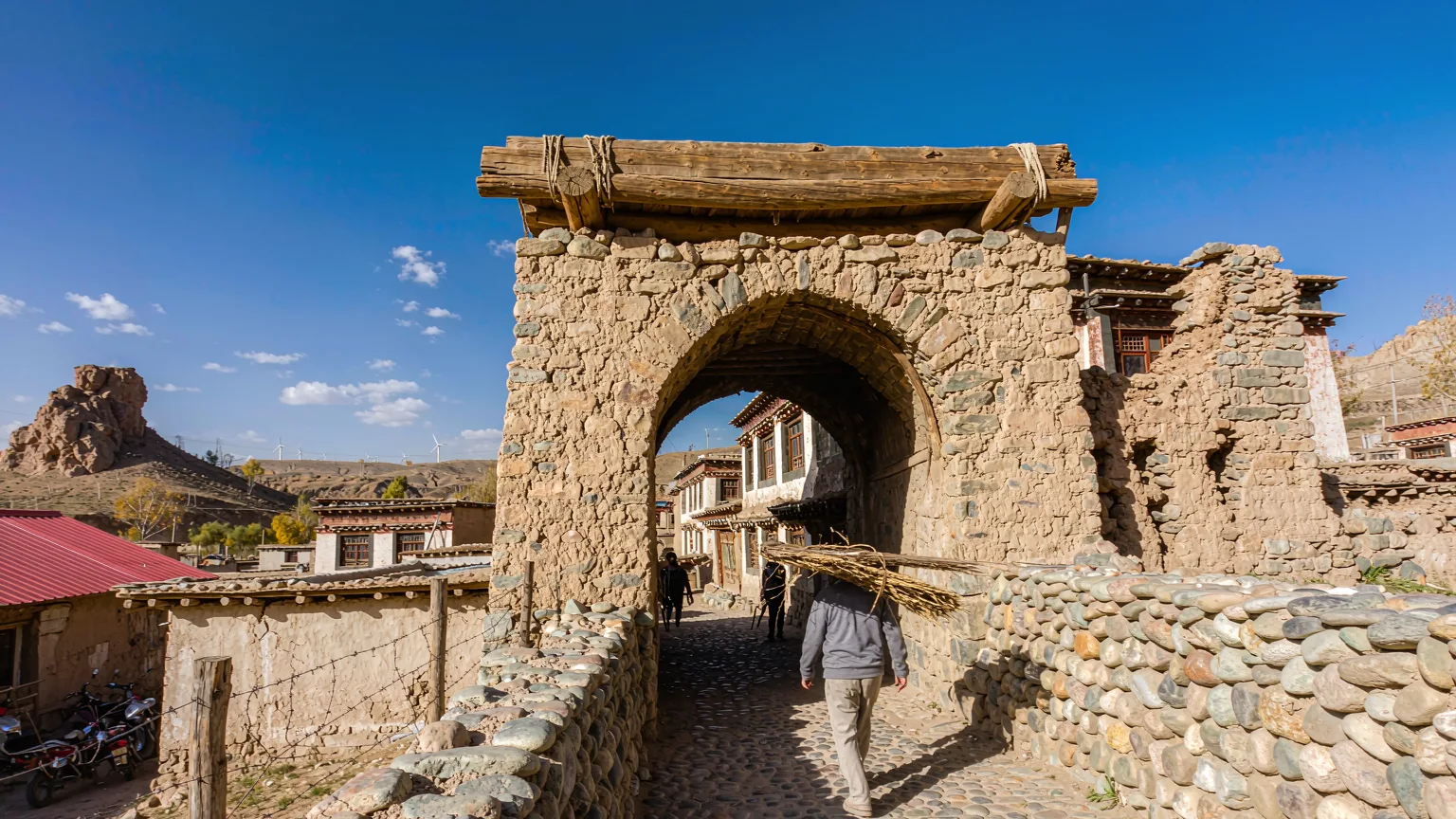 Visitor entering Dabancheng Ancient Town with wind turbines in background