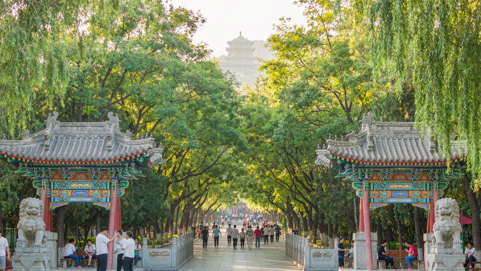 Visitors entering Daguan Pavilion Park through traditional gate with guide