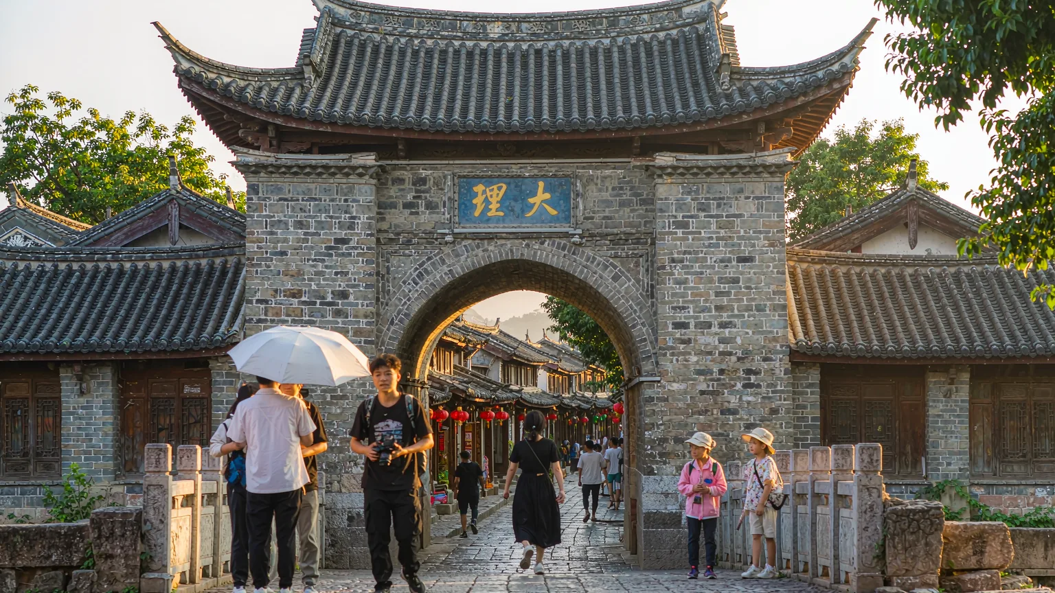 Visitors entering Dali Ancient City through ancient gate with guide