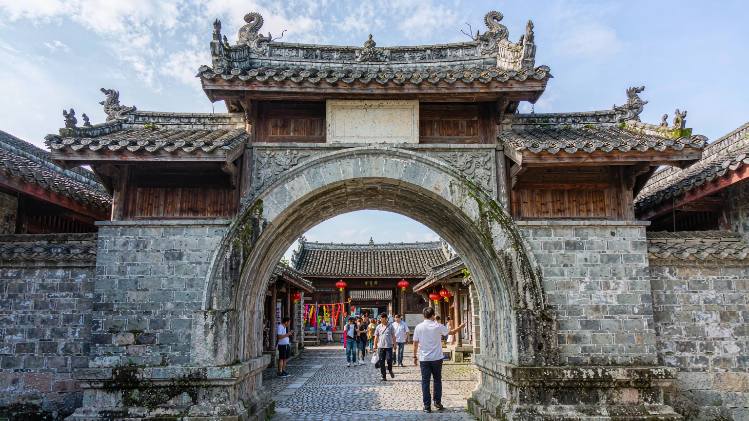 Visitors entering Dapeng Fortress through the ancient south gate with a guide