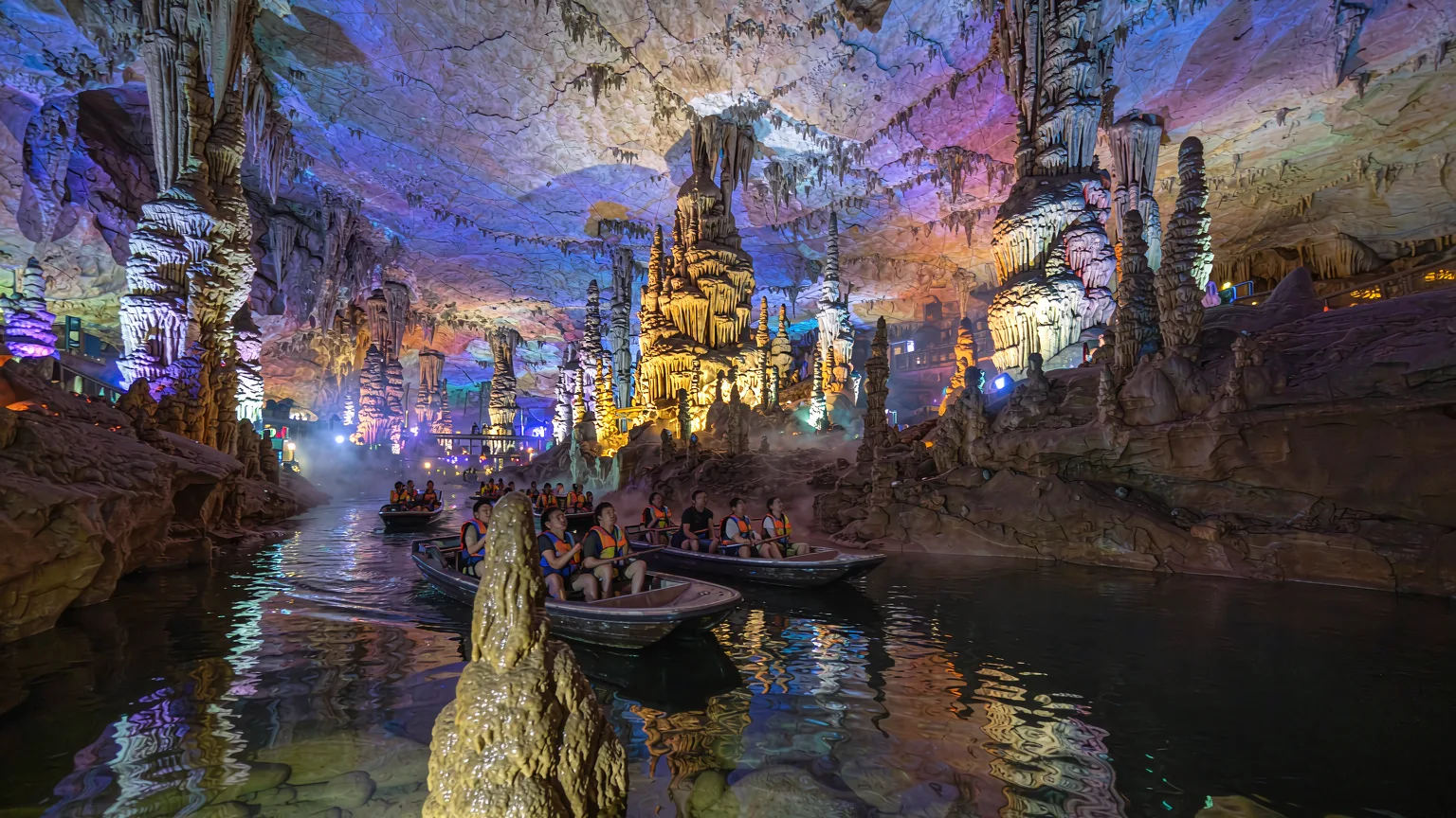 Boat tour inside Dragon Palace cave with illuminated stalactites