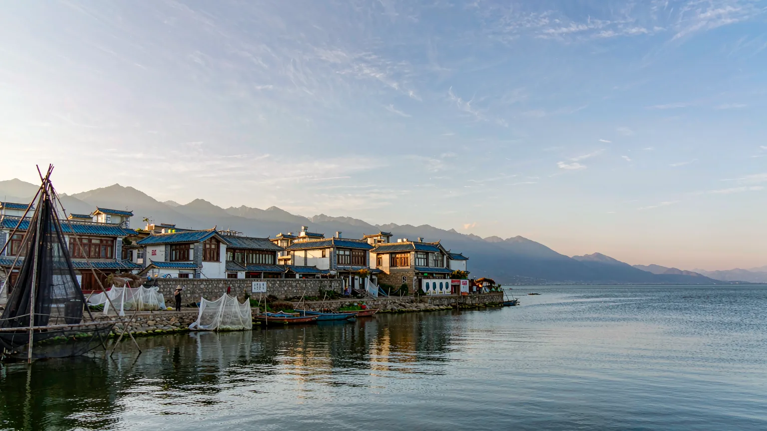 Bai village with white houses on Erhai Lake shore, mountains behind