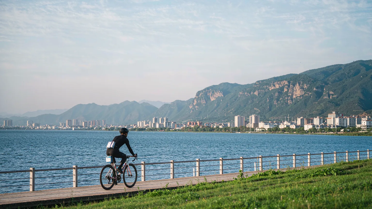 Cyclist on a scenic path along Erhai Lake with mountains ahead