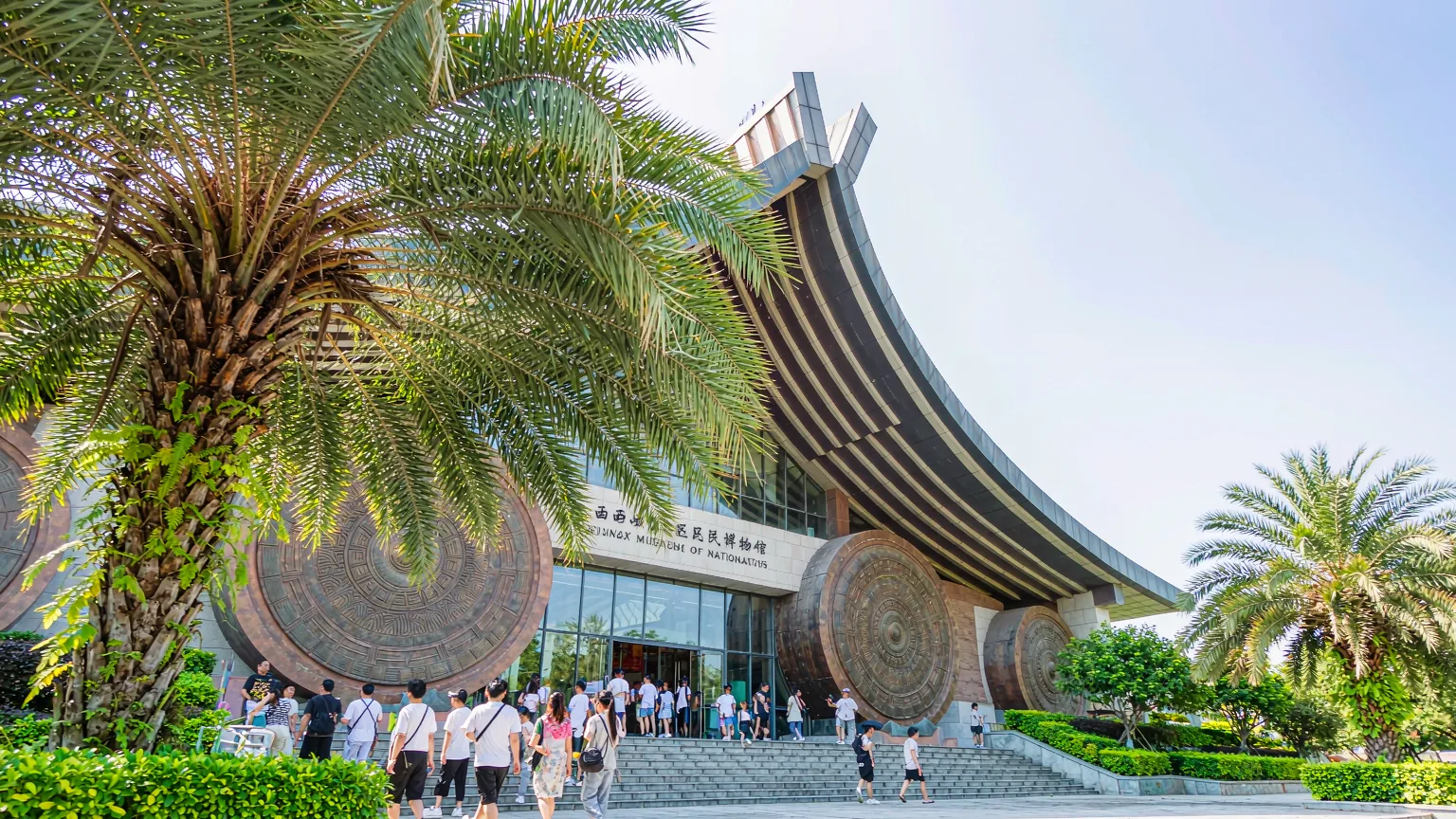 Visitors walking up steps to museum entrance under bronze drum facade