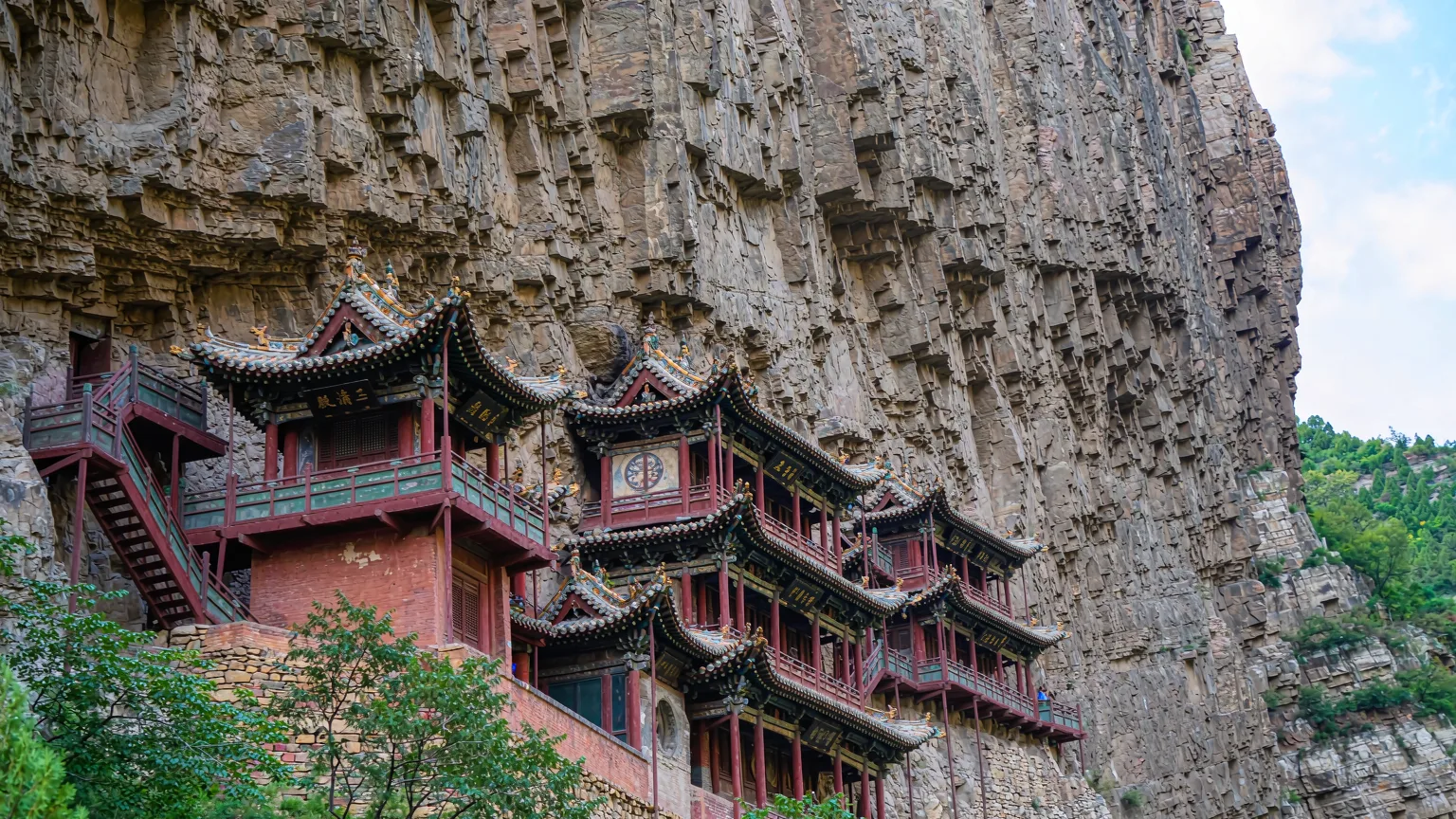Multi-tiered wooden Hanging Temple built into vertical rock face with balconies
