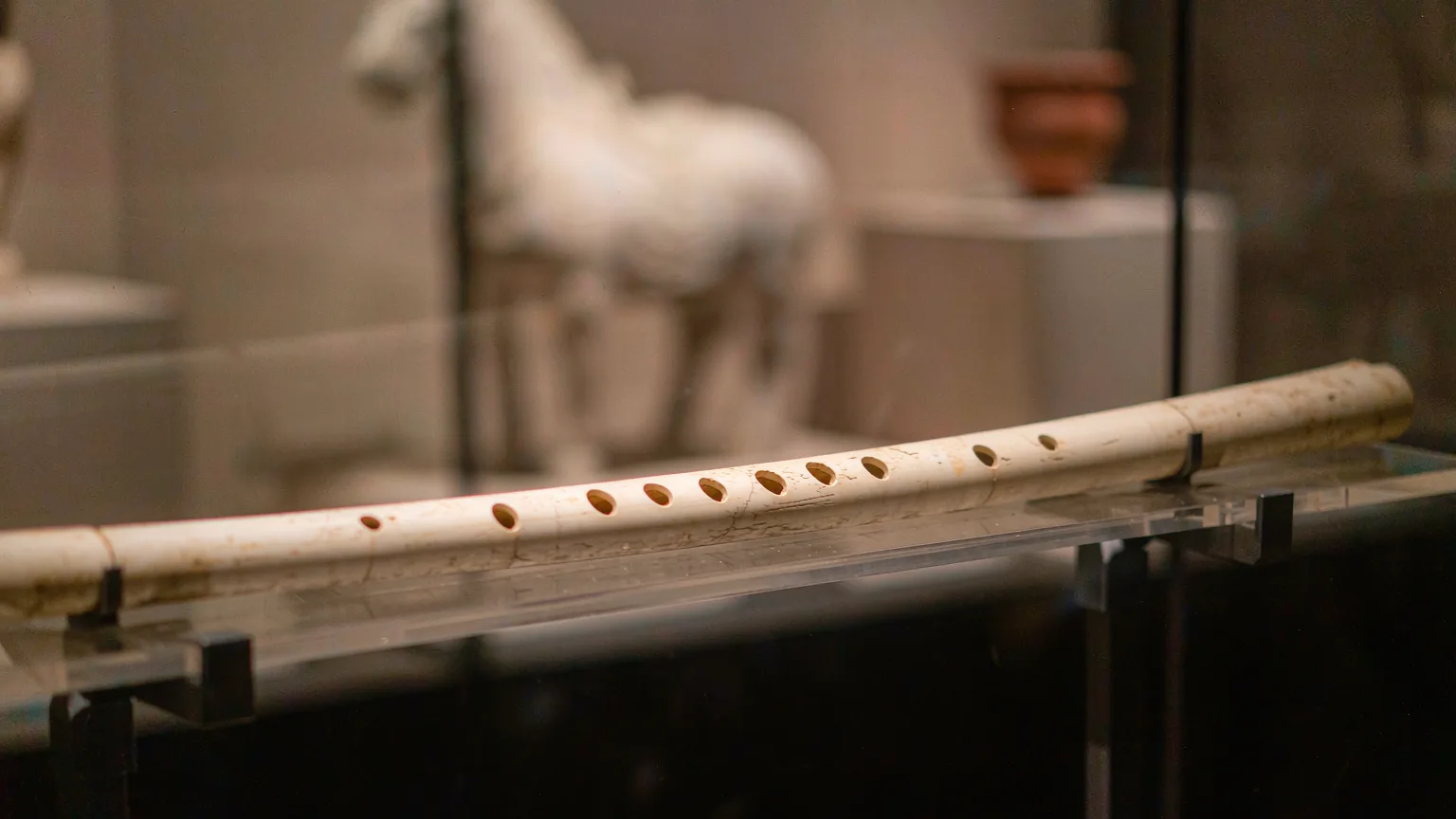 Close-up of ancient Jiahu bone flute in illuminated display case at Henan Museum