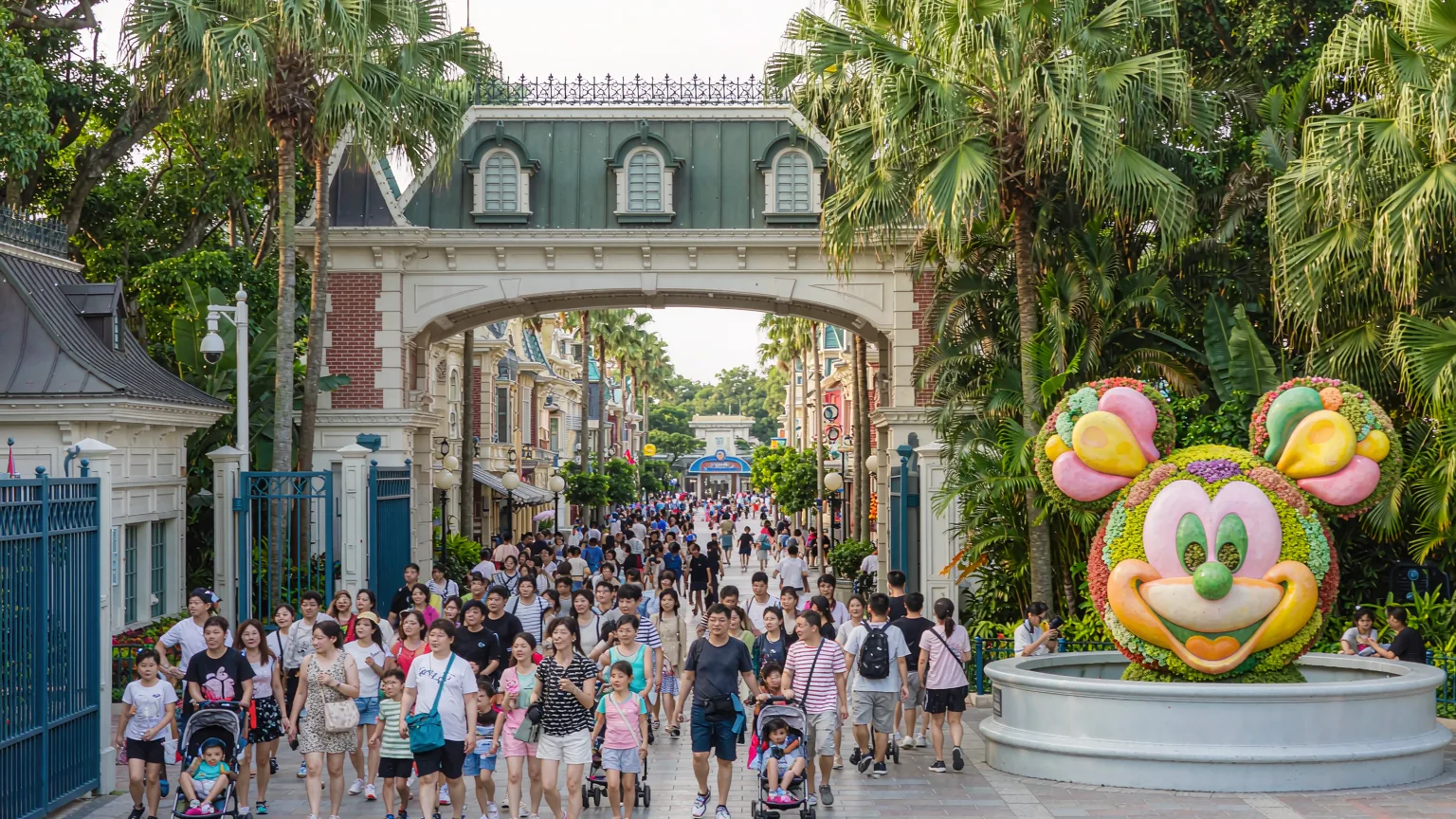 Visitors entering Hong Kong Disneyland under the railroad station with floral Mickey