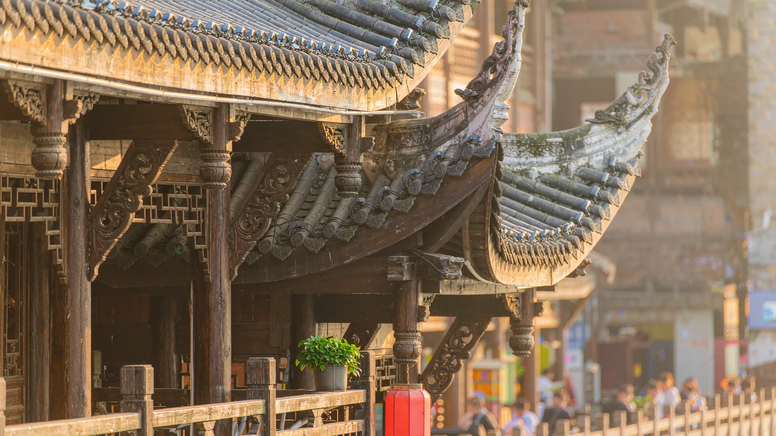 Close-up of carved wooden eaves and red lantern on a Hongya Cave balcony