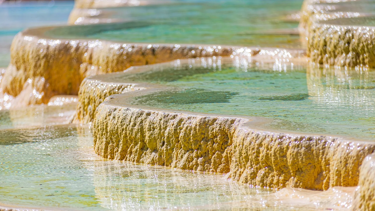 Close-up of golden travertine ridges and turquoise water in Huanglong's pools