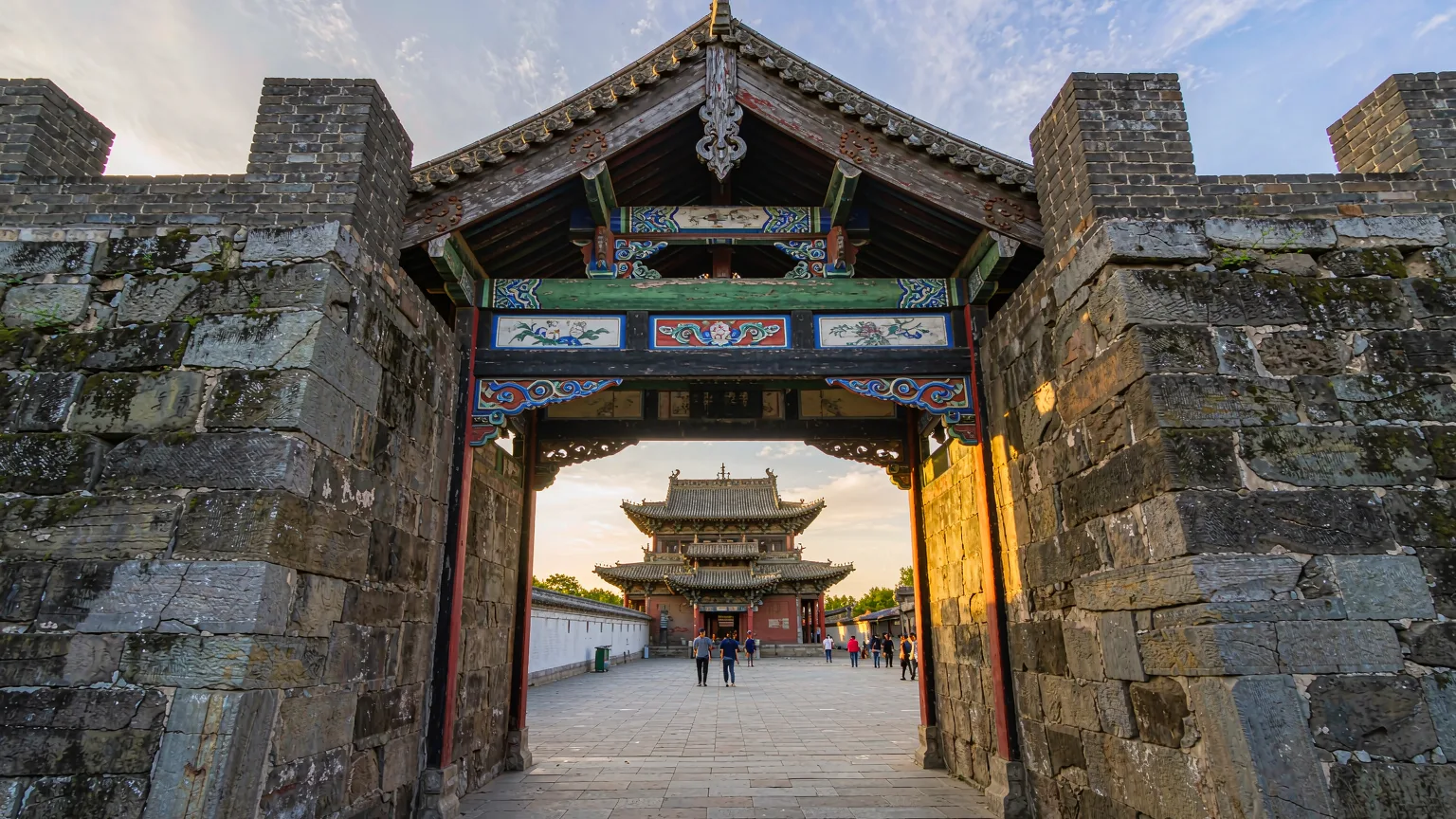Travelers entering Huayan Temple through its old stone gateway in Datong