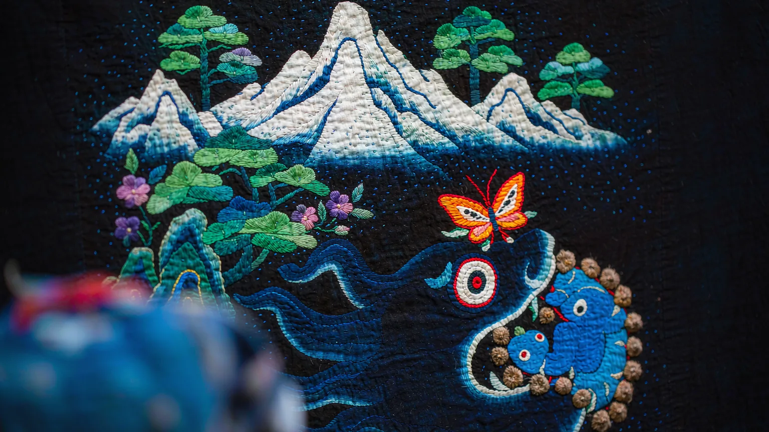 Naxi embroidery close-up featuring Jade Dragon Snow Mountain motif