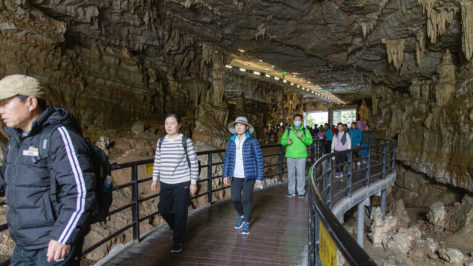 Tourists on a boardwalk inside Jiutian Cave with guide