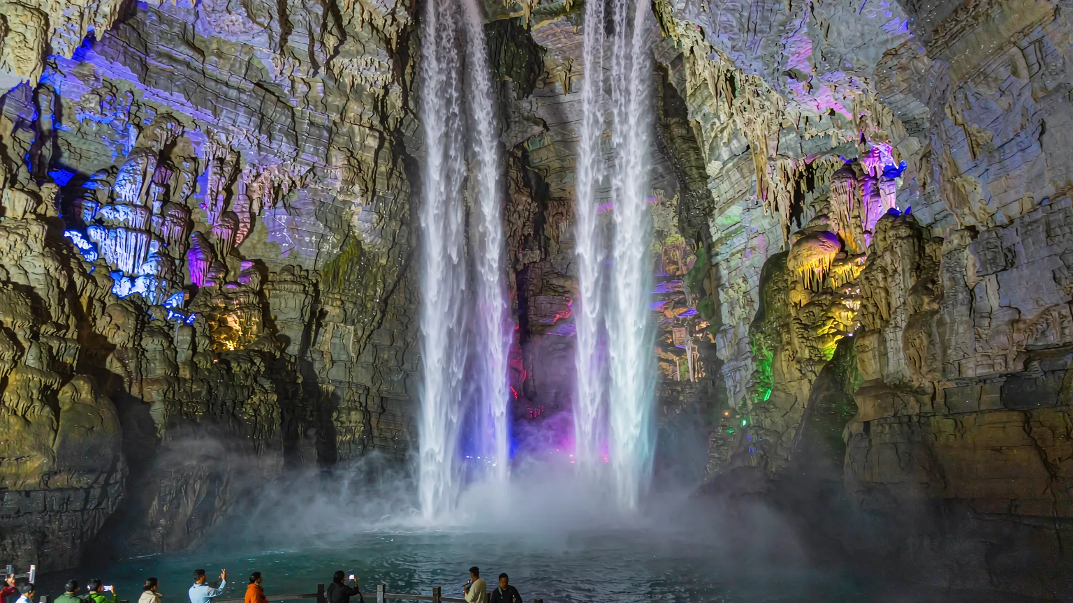 Twin waterfalls cascading into a cavern pool at Jiuxiang