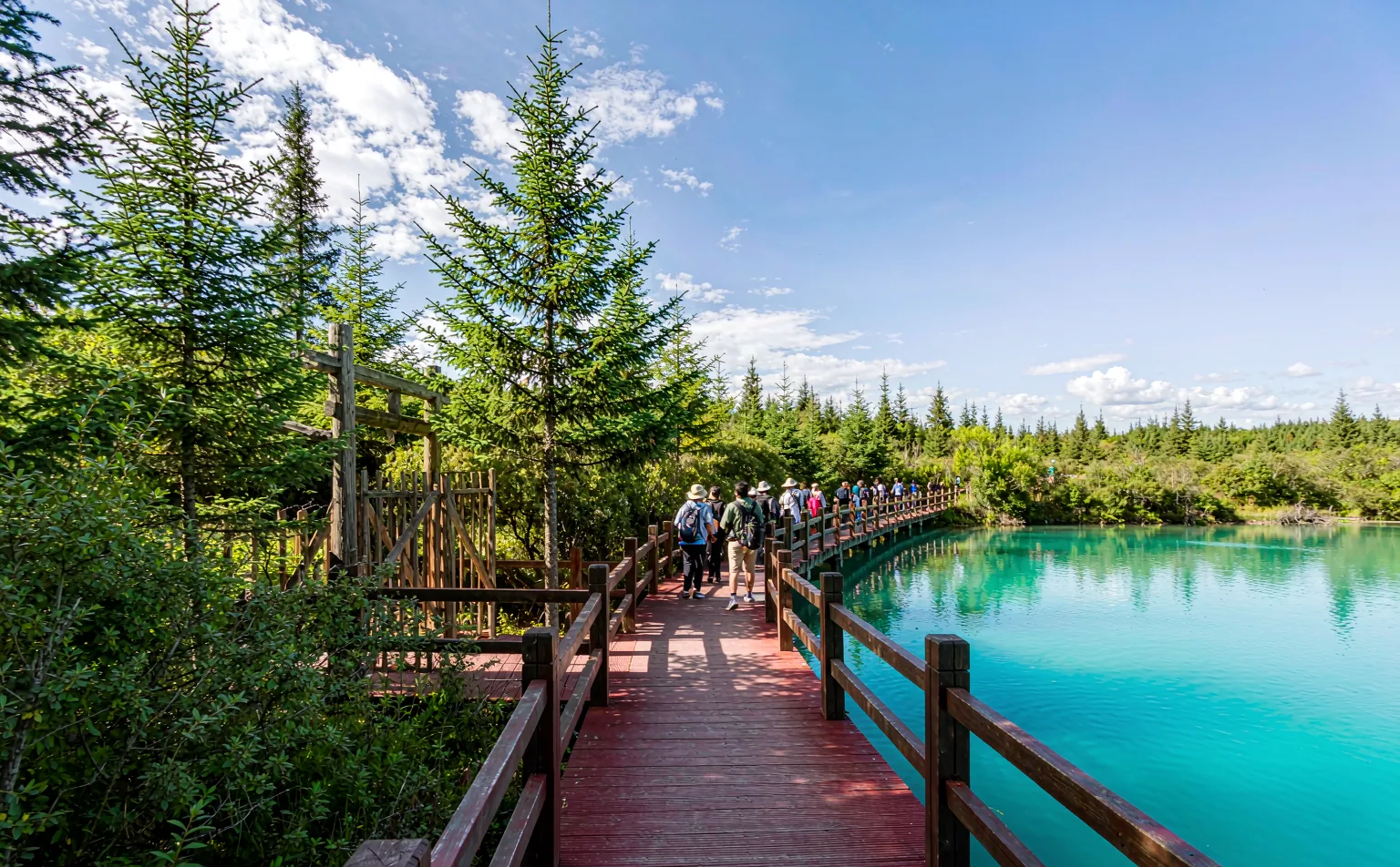 Wooden boardwalk between turquoise lakes in Jiuzhaigou Valley