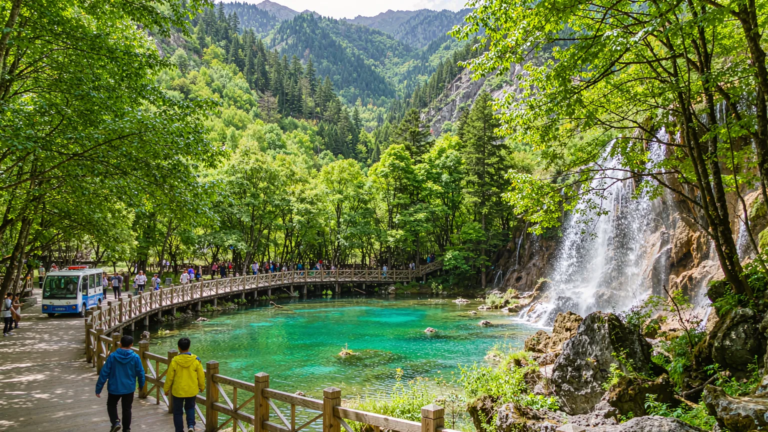 Tourists on a boardwalk with a view of lakes and shuttle bus in Jiuzhaigou