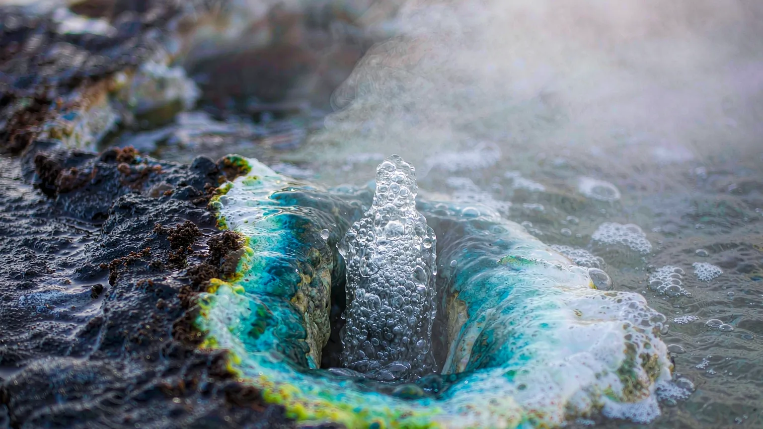 Close-up of bubbling mineral water and steam at Julong Hot Springs volcanic rock