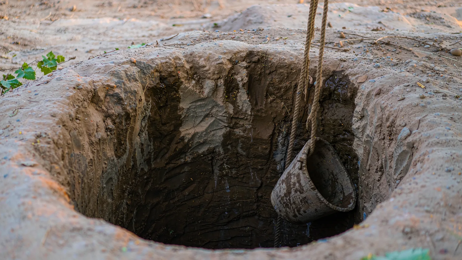 Close-up of Karez well opening with rope and bucket in desert