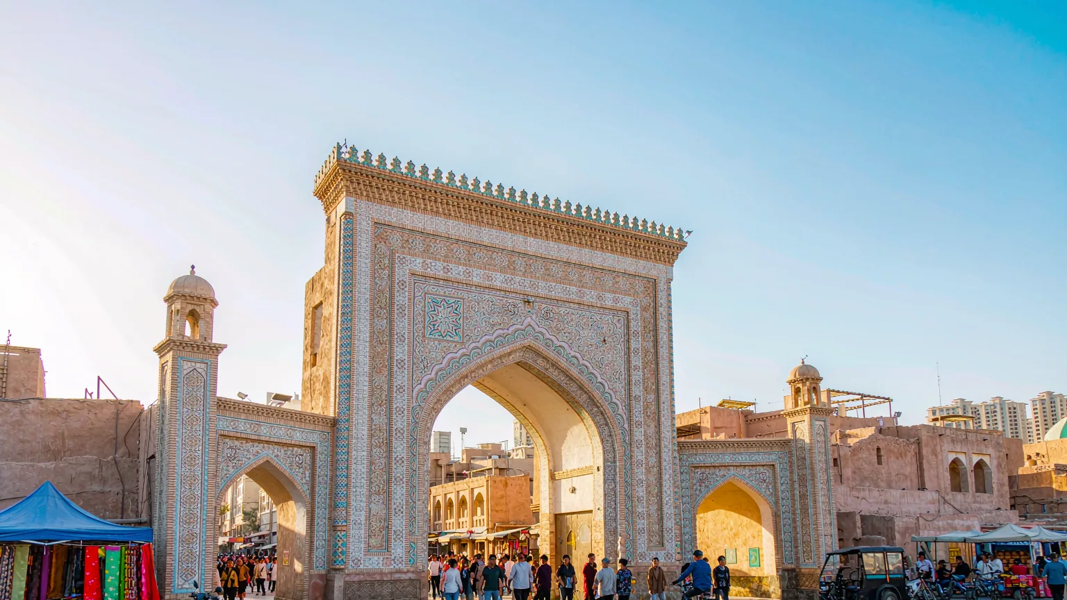 Ornate entrance gate of Kashgar Old Town with visitors and vendors