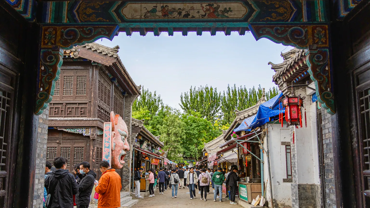 Tourists entering Lao Daowai district through a decorative archway into historic lanes