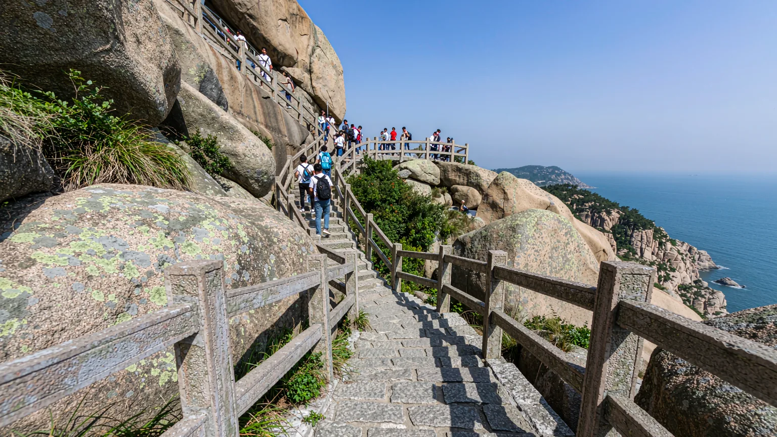 Stone pathway winding up Laoshan with hikers and sea view