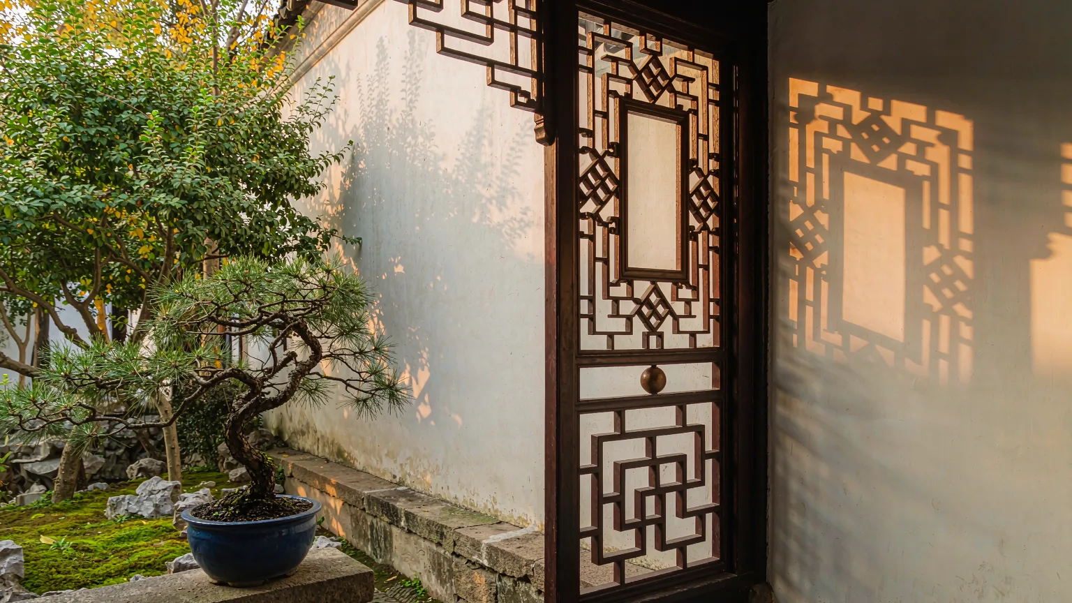Detailed lattice window and bonsai in a quiet corner of Lingering Garden