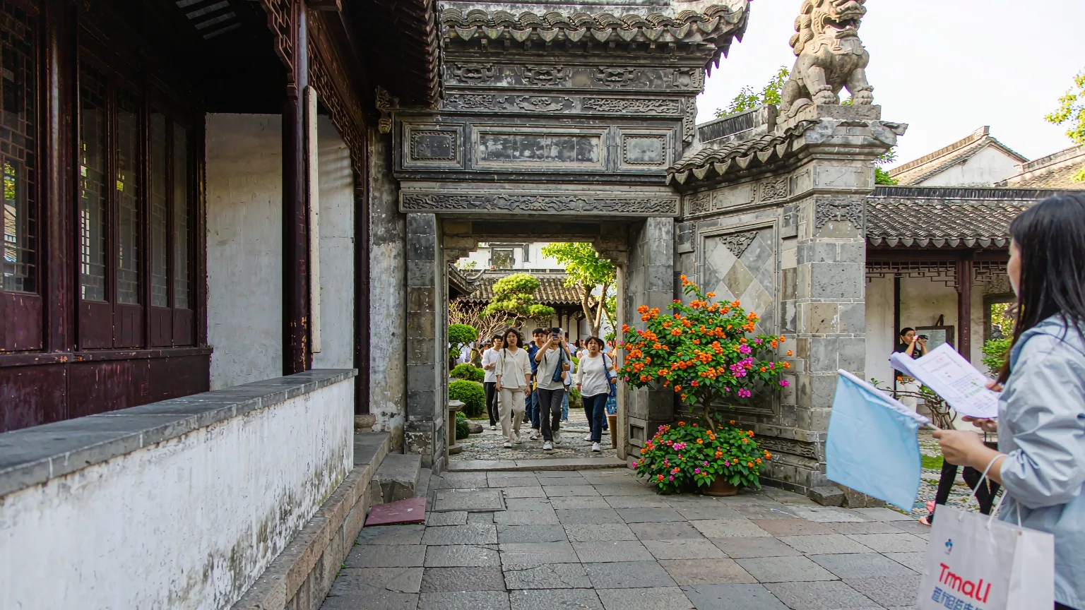 Visitors entering Lingering Garden through traditional gate with stone lion