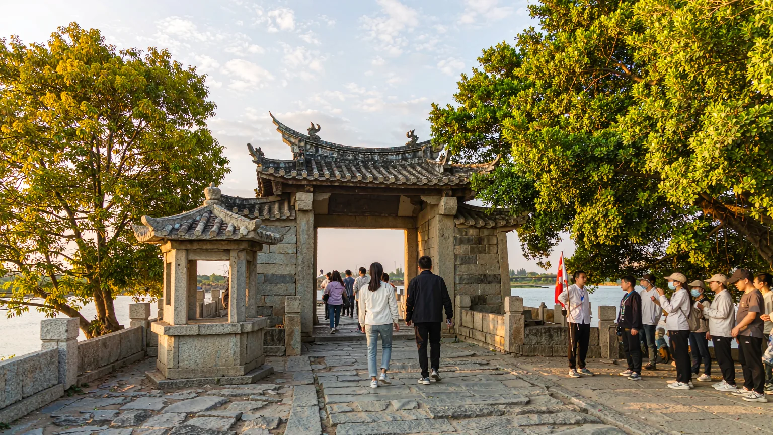 Visitors walking on Luoyang Bridge's stone pathway with guide