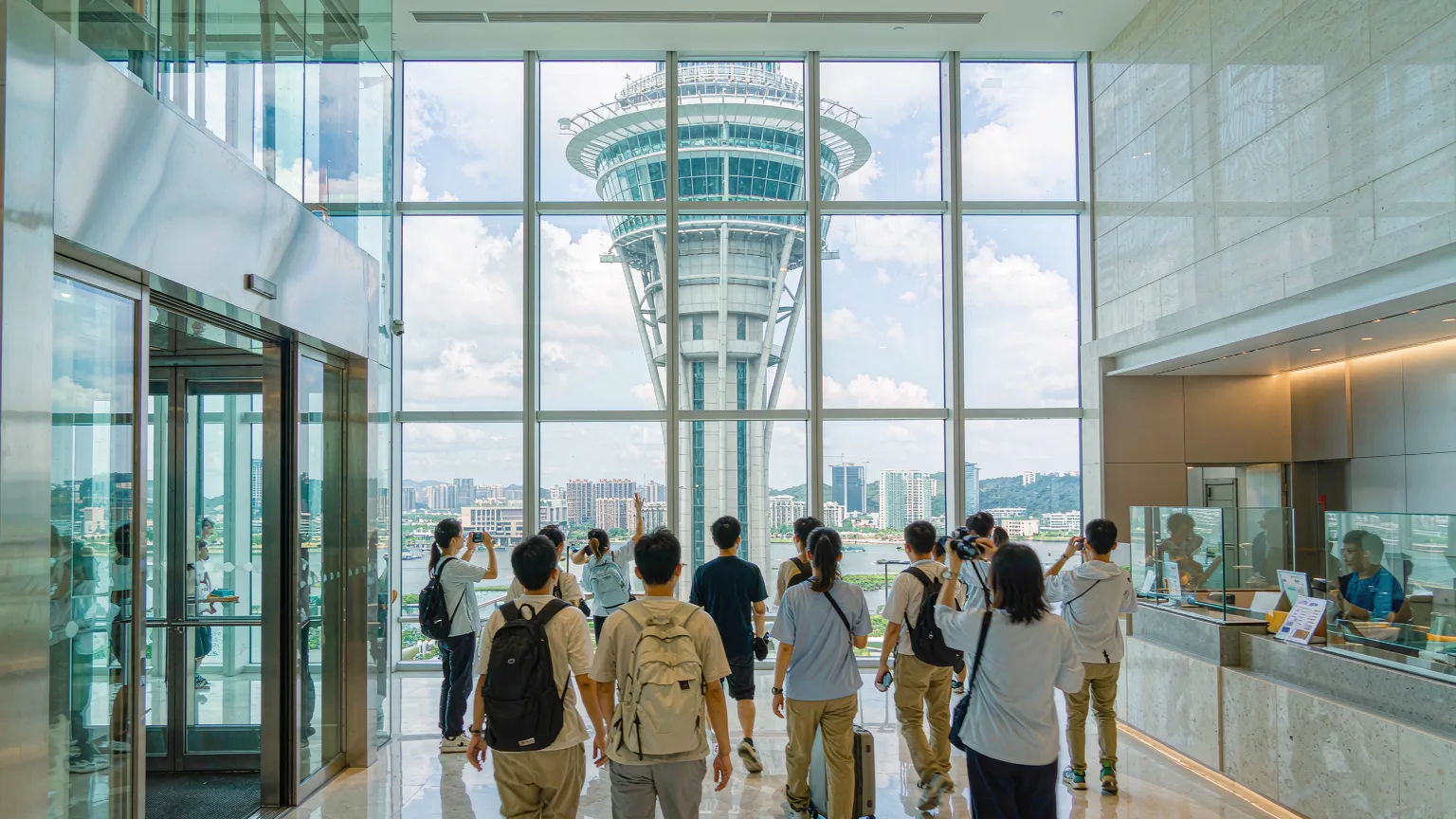 Visitors at Macau Tower entrance lobby with glass elevator