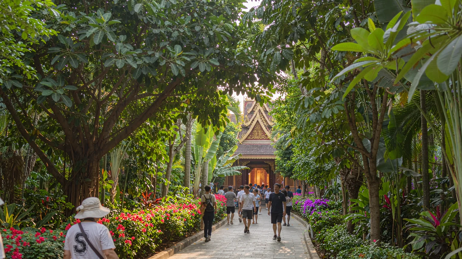 Visitors walking on shaded stone path in Manting Park with temple ahead