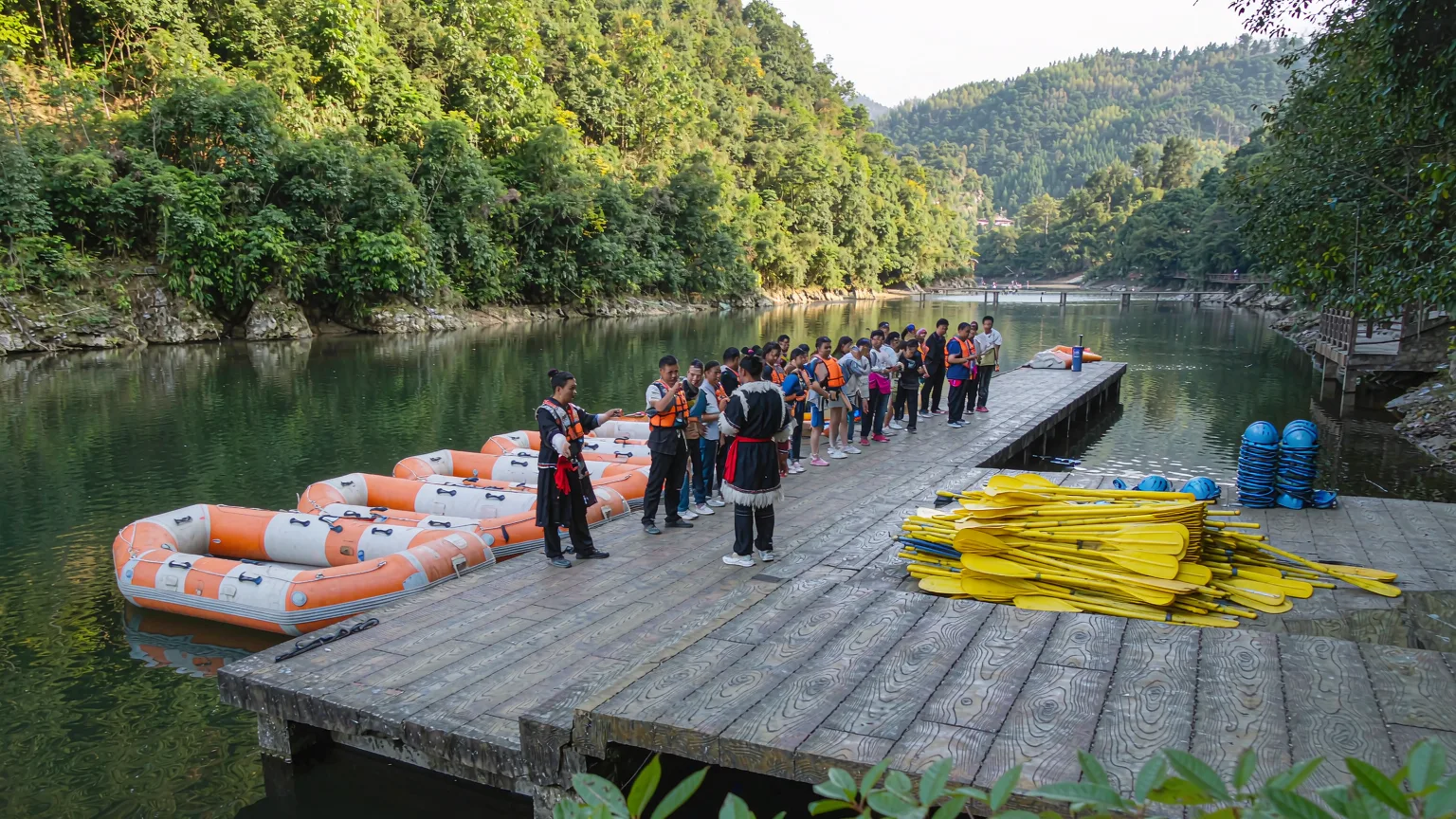 Tourists boarding rafts at a wooden dock on Maoyan River with a Tujia guide