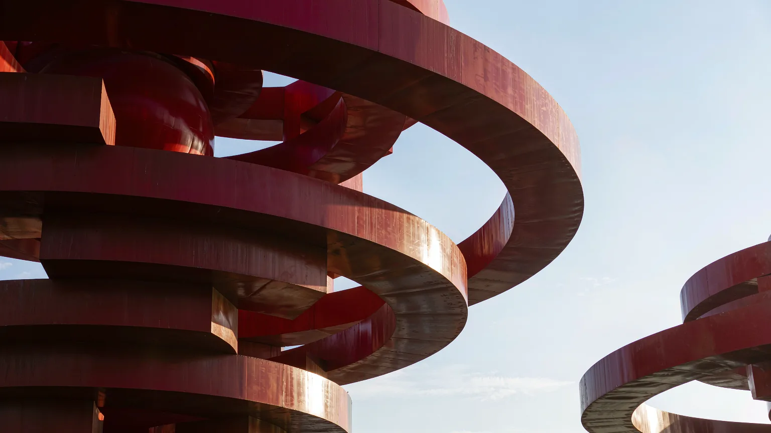 Close-up of red May Wind sculpture's swirling steel ribbons