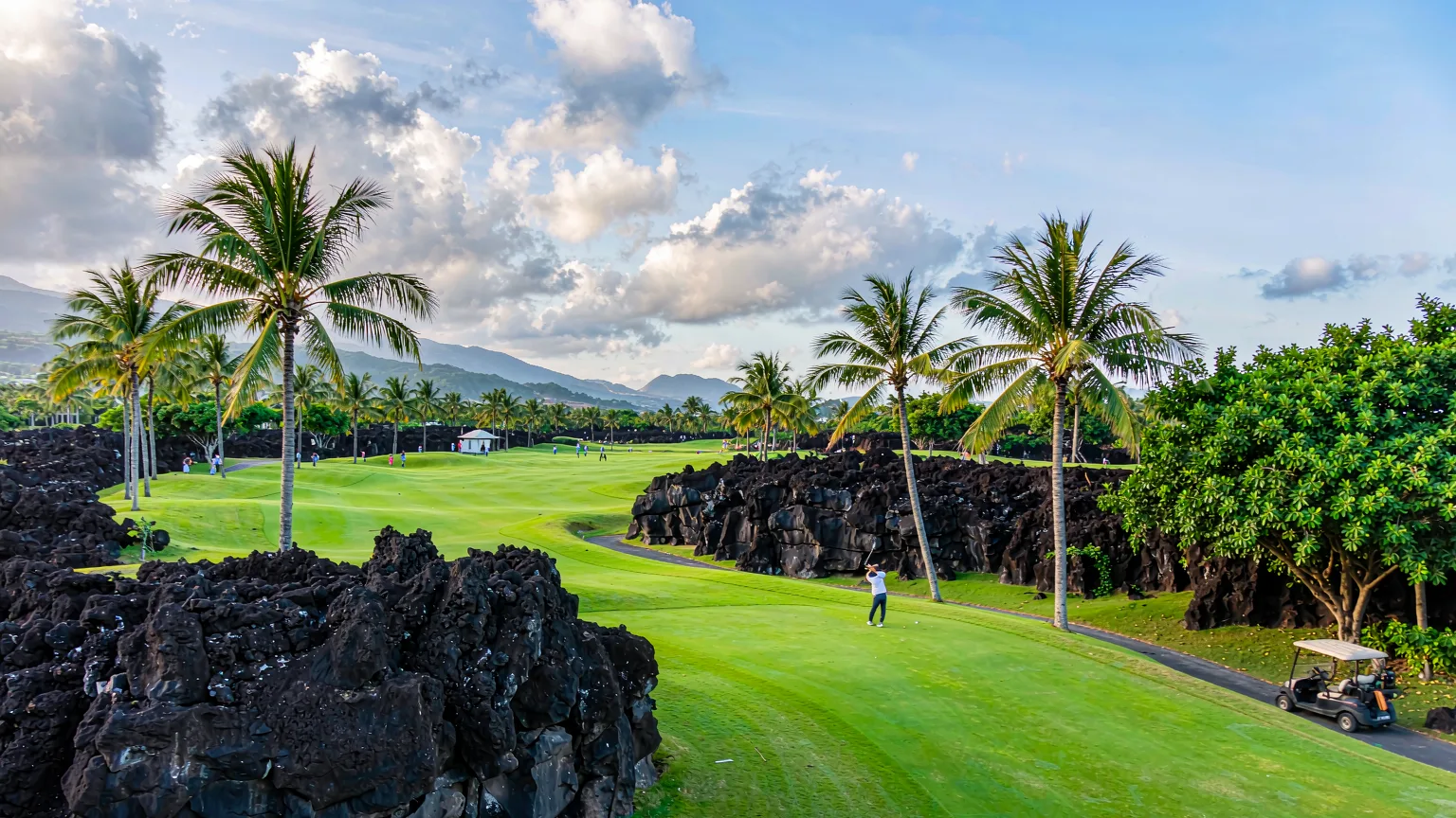 Golfers on the Blackstone Course with volcanic rock at Mission Hills Haikou