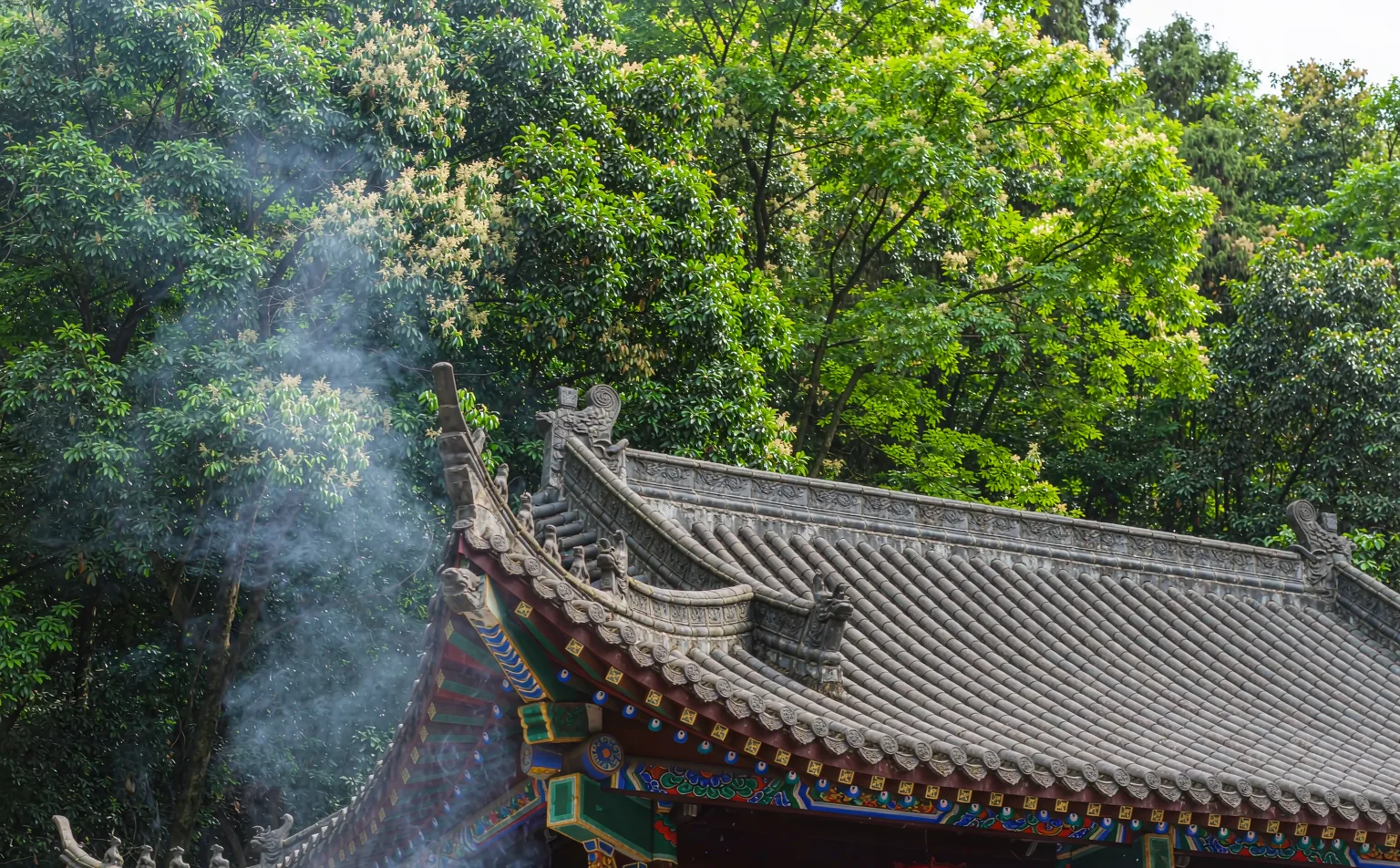 Taoist temple roof with upturned eaves and incense smoke on Mount Qingcheng