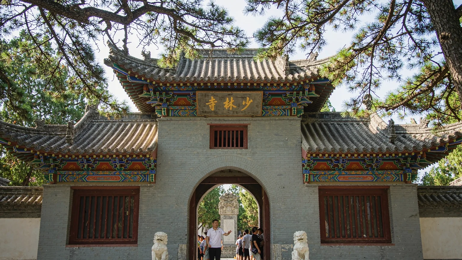 Visitors entering Shaolin Temple through grand gate with guide