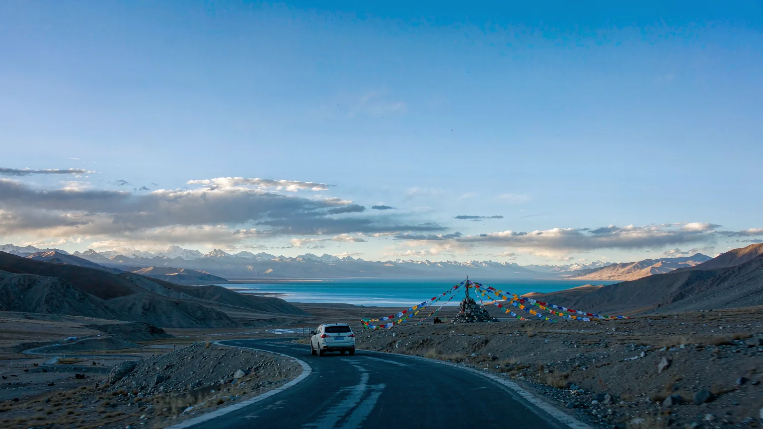 Private vehicle driving toward Namtso Lake on a high mountain pass from Lhasa