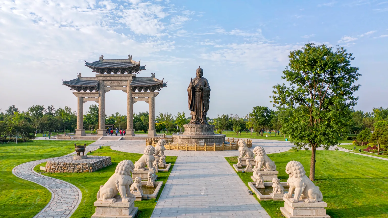 Tourists walking ceremonial path toward Nishan Sacred Land with statue in distance