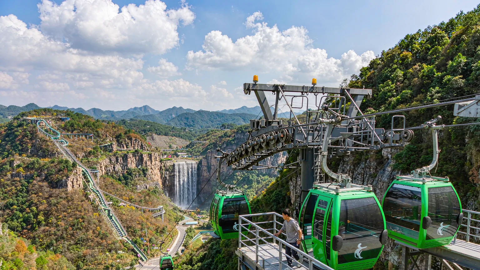 Visitors boarding aerial cable car at OCT East with theme park views