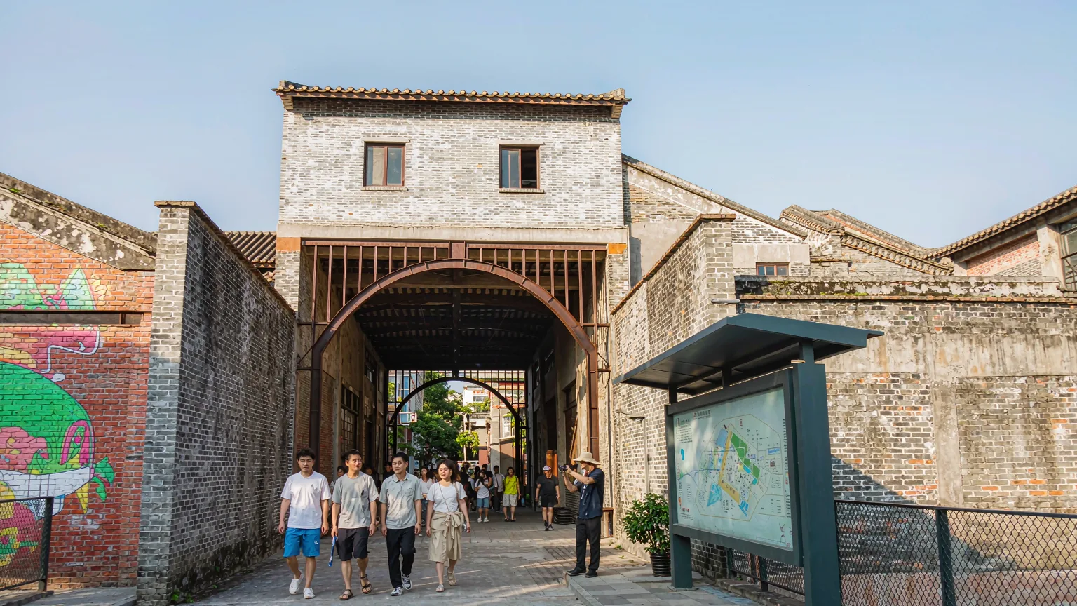 Visitors at the entrance of OCT Loft Creative Culture Park with graffiti and brick walls