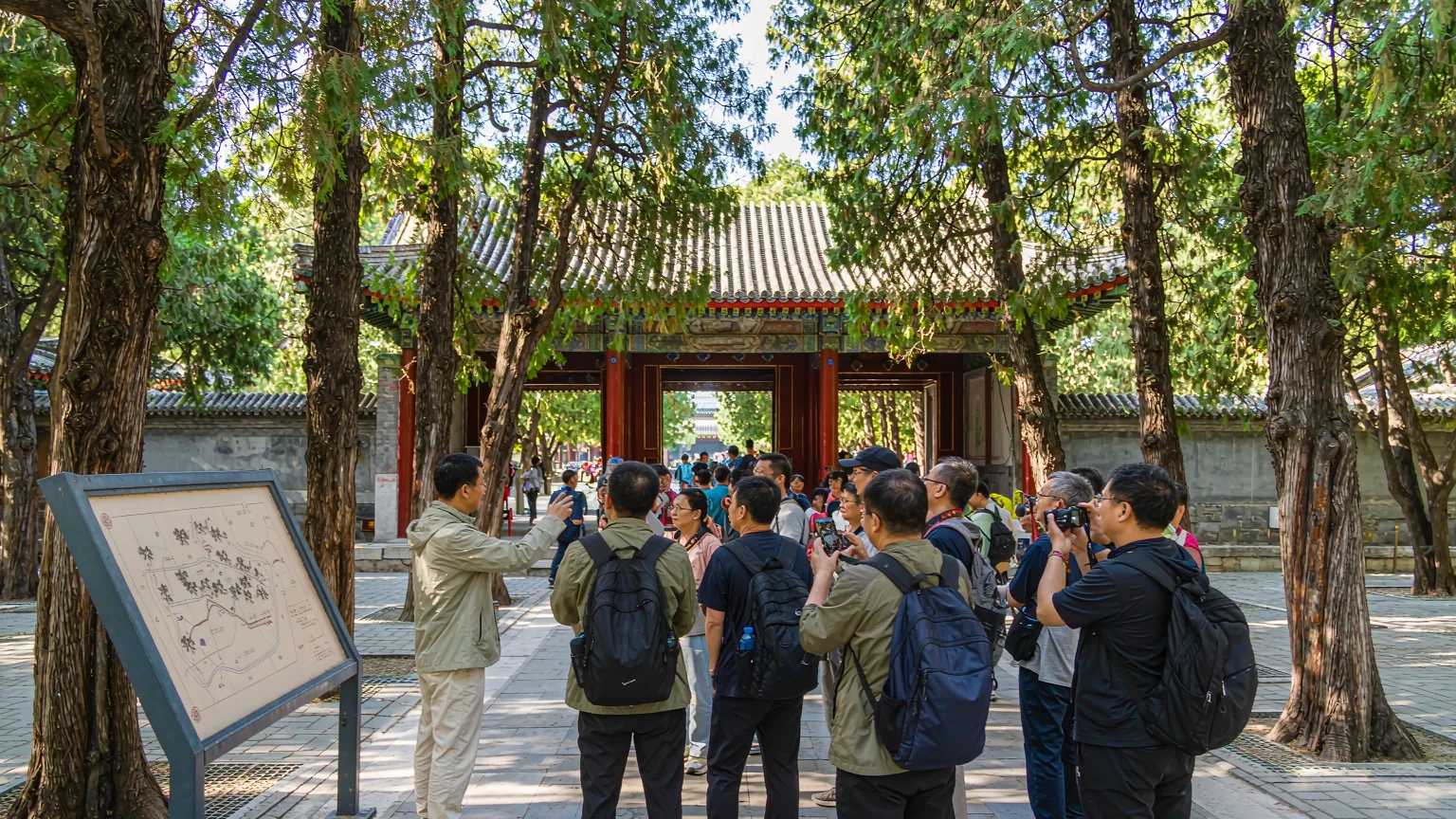 Tourists entering Old Summer Palace through south gate on tree-lined path