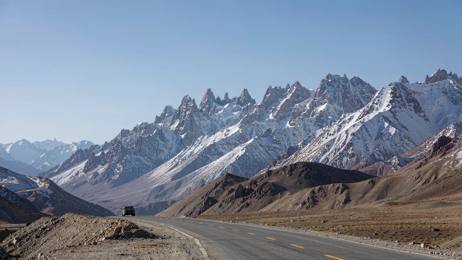 Vehicle driving on Karakoram Highway through Pamir Plateau with snow peaks