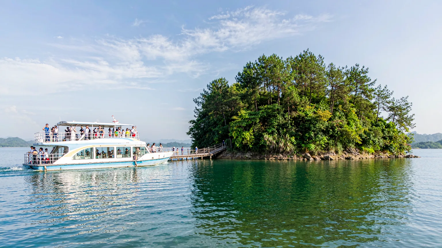 Tourist boat approaching a green island on Qiandao Lake