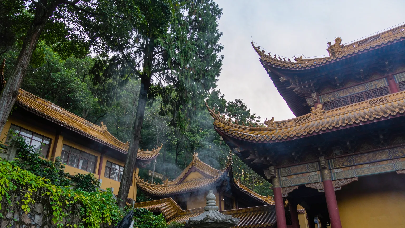 Hongfu Temple courtyard with incense smoke and camphor trees in Qianling Mountain Park