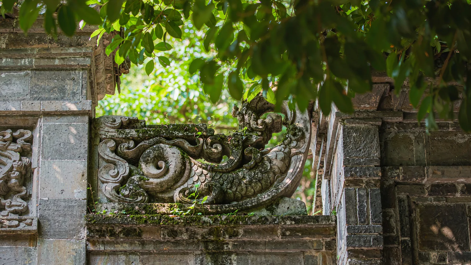Weathered stone carving with dragon motif on a temple wall at Qingxiu Mountain