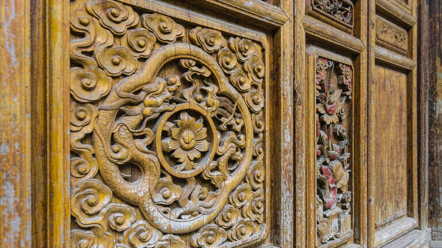 Detailed wooden carvings on a temple door in Qingyan Ancient Town